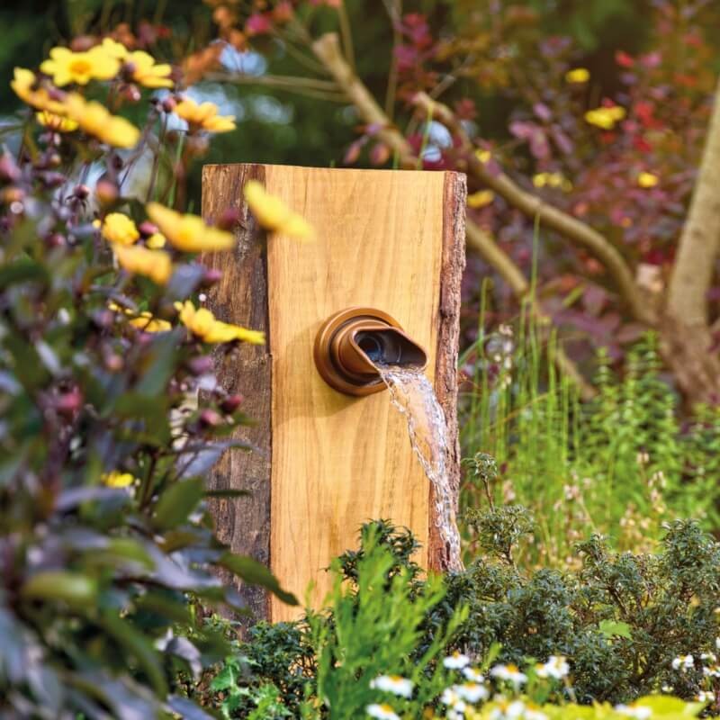 Wylewka Wall Spout Square copper Oase-84180  na drewnianym cokole wśród kwiatów